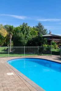 een blauw zwembad voor een hek bij Antares Homestay in Renwick