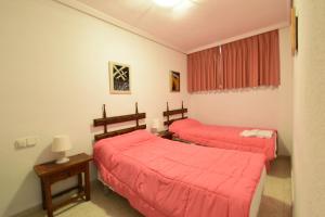 two beds in a room with red sheets at Las Tejas - Fincas Arena in Benidorm
