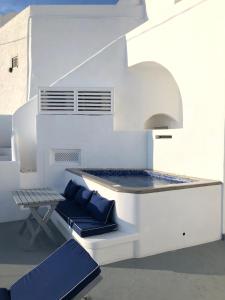 a white house with a bench and a table at Altana Cliffside Villas in Imerovigli