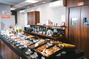 a buffet line with different types of pastries and drinks at Hotel 10 Blumenau in Blumenau