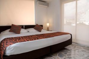 a bedroom with a large bed with a large window at Hotel Flamingo Cali in Cali