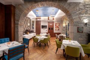 a restaurant with tables and chairs and a stone wall at Hotel Solun in Trieste