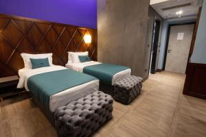 a hotel room with two beds and a stool at Hotel Solun in Trieste