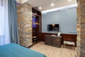 a bedroom with a stone wall and a television at Hotel Solun in Trieste