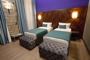 a hotel room with two beds and a stool at Hotel Solun in Trieste