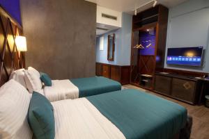 a hotel room with two beds and a flat screen tv at Hotel Solun in Trieste