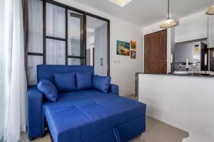- un canapé bleu dans un salon avec une cuisine dans l'établissement PALMYRAH SURIN, MODERN 1BR with Terrace, 150 meters to Surin Beach, à Surin Beach
