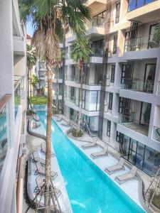 an apartment building with a swimming pool and palm trees at PALMYRAH SURIN, MODERN 1BR with Terrace, 150 meters to Surin Beach in Surin Beach