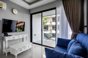 uma sala de estar com um sofá azul e uma televisão em PALMYRAH SURIN, MODERN 1BR with Terrace, 150 meters to Surin Beach em Praia de Surin