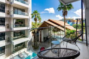 um apartamento varanda com duas cadeiras e uma mesa em PALMYRAH SURIN, MODERN 1BR with Terrace, 150 meters to Surin Beach em Praia de Surin