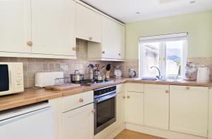 a white kitchen with white cabinets and a window at The Neuadd Cottages in Crickhowell +10 photos