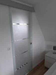 a glass shower door in a white bathroom at Backbord in Wangerland