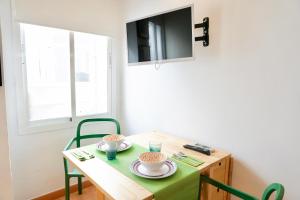 a small table with green chairs and a television at Alemania & SOHO by ELE Apartments in Málaga