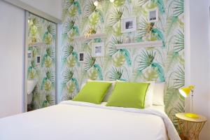 a bedroom with a white bed with a tropical wallpaper at Alemania & SOHO by ELE Apartments in Málaga