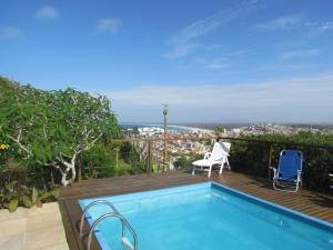 a swimming pool on a deck with a view of the city at Casa Pontal do Atalaia in Arraial do Cabo