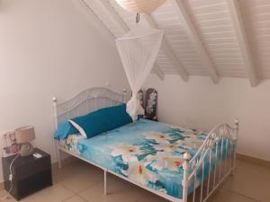 Schlafzimmer mit einem Bett mit blauer Tagesdecke und Blumen in der Unterkunft La Port-Louisienne in Port-Louis