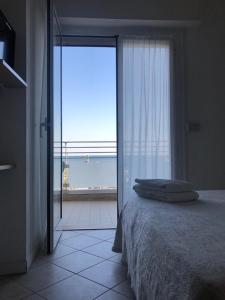 a bedroom with a bed and a large window at Hotel Alda in Cervia