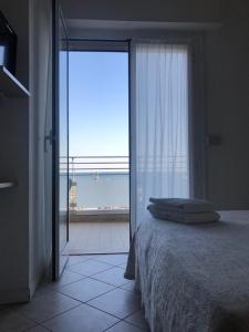 ein Schlafzimmer mit einem Bett und einem großen Fenster in der Unterkunft Hotel Alda in Cervia