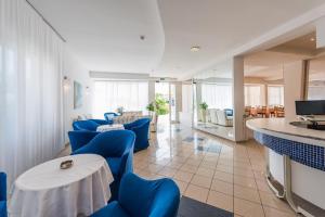 une salle d'attente avec des chaises bleues et un comptoir dans l'établissement Hotel Alda, à Cervia