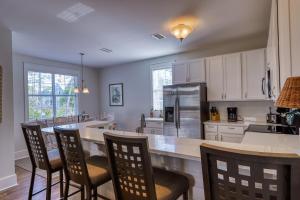 a kitchen with white cabinets and a large island with chairs at Barefoot Cottages #C56 in Highland View