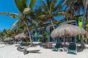 un edificio en la playa con sillas y palmeras en Del Sol Beachfront, en Akumal