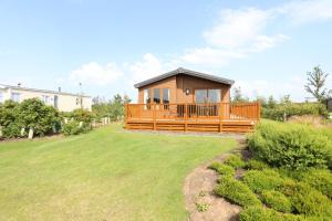 ein Haus mit einer großen Terrasse auf einem Rasen in der Unterkunft Cosy Dreams Lodge in Beal