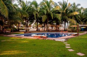 a swimming pool in a yard with palm trees at Bambuddha Centro Holistico in Barra Vieja