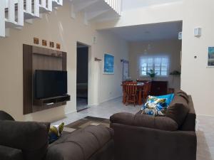 sala de estar con sofá y TV de pantalla plana en Casa de praia, en Guaratuba