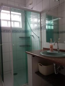 uma casa de banho com um lavatório e uma cabina de duche em vidro. em Casa de praia em Guaratuba