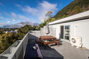 a balcony with a wooden table and bench on a building at Central Mountain View Paradise in Queenstown