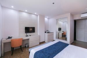 um quarto com uma cama grande e uma televisão em La Maja Rica Hotel em Tarlac