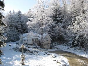 a house covered in snow next to a river at Mountain Valley Retreat in Killington