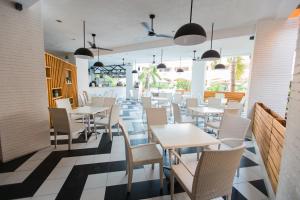 um restaurante com mesas e cadeiras brancas e janelas em La Maja Rica Hotel em Tarlac