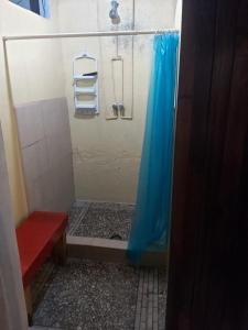 a shower with a blue shower curtain and a red bench at El Sunset Hostel in Puerto Vallarta