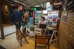 two men standing at a table with a laptop at Biergarten Hostel in Abraão