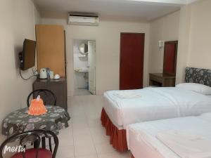 a hotel room with two beds and a table and a television at Baan Boa Guest House in Patong Beach