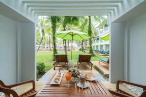 a wooden table with a green umbrella on a patio at The Briza Beach Resort, Khao Lak SHA Extra Plus in Khao Lak