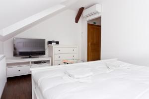 a white bedroom with a bed and a flat screen tv at Havířská bouda in Kutná Hora