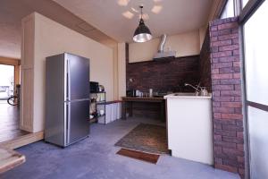 a kitchen with a refrigerator and a brick wall at Guest House Kadoyasu in Kanazawa