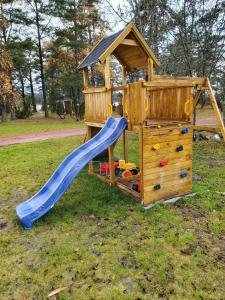 a wooden playground with a slide and a playset at Söderö stugby in Finström