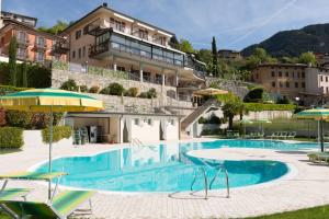 einem Pool mit Stühlen und Sonnenschirmen vor einem Gebäude in der Unterkunft Hotel La Fenice e Sole in Tremosine sul Garda