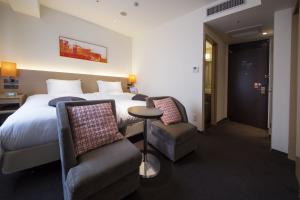Habitación de hotel con 1 cama y 2 sillas en HOTEL FORZA HAKATAEKI CHIKUSHI-GUCHI Ⅰ en Fukuoka