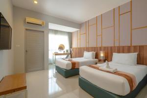 a hotel room with two beds and a television at Hug Nimman Hotel in Chiang Mai