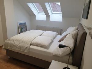 Schlafzimmer mit einem Bett mit weißer Bettwäsche und einem Fenster in der Unterkunft Apartment Stockerau in Stockerau
