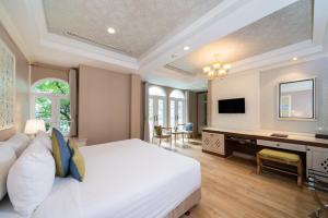a bedroom with a large bed and a desk at La Petite Salil Sukhumvit 8 in Bangkok