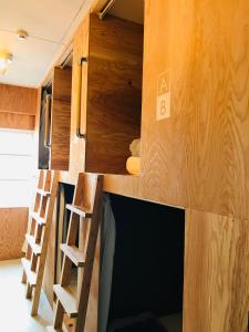 a room with a tv and some wooden walls at MEEDAFU'S YUI HOSTEL and COFFEE in Yoron
