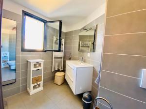 a bathroom with a sink and a toilet and a window at Appartement neuf tout confort en bord de mer in Propriano