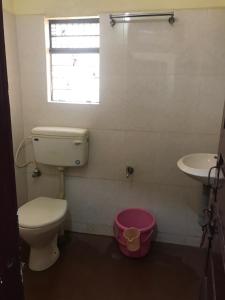 a bathroom with a toilet and a sink and a window at Shri Vasant Lodge in Hubli