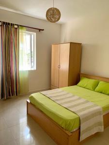 a bedroom with a bed with green sheets and a window at Villa Oliveraie Apartments in Flic-en-Flac