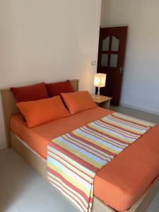 a bed with orange pillows and a colorful blanket on it at Villa Oliveraie Apartments in Flic-en-Flac